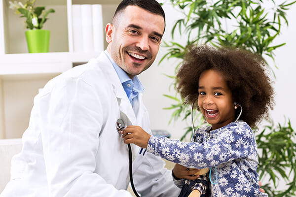 a male doctor letting a child play with stethoscope